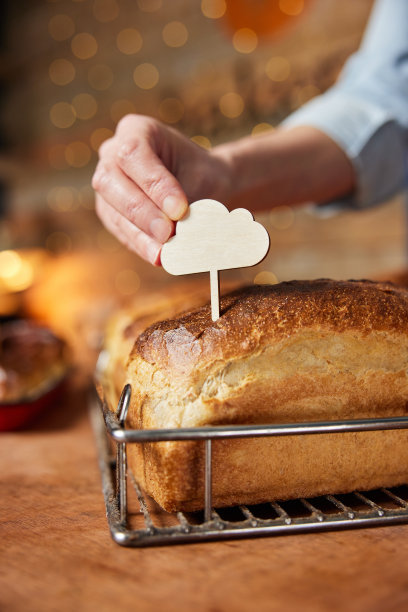 面包店的销售助理正在把空白标签放入刚烤好的酸面包中图片下载