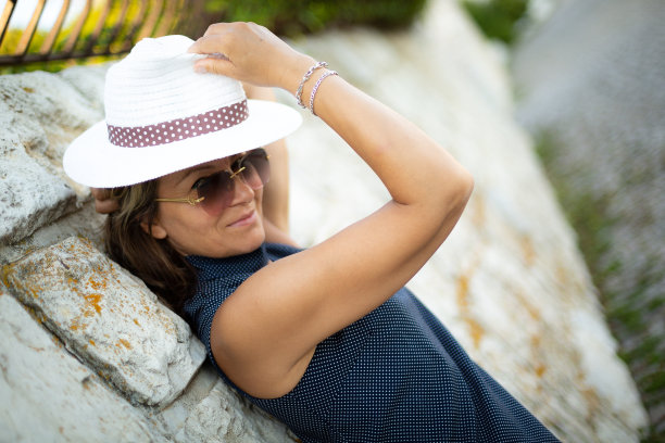 女人戴着夏天的帽子在海滩上度假，站着一张快乐的脸，微笑着自信的微笑图片下载