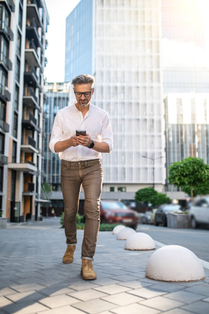 一个穿白衬衫的男人走在街上发短信图片下载