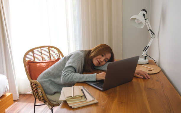 一名年轻女子累了，在家里用笔记本电脑工作时打了个盹图片下载