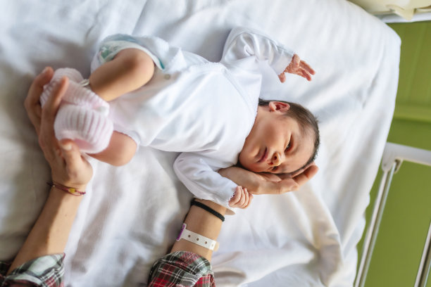 医院里一个刚出生的男孩的照片，他的婴儿床上躺着一件白色的紧身衣图片下载