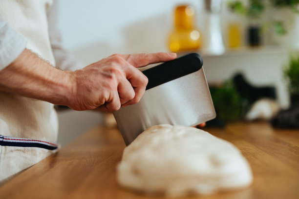 特写镜头是一个不知名的男人在厨房里切面团图片下载