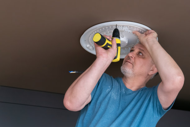 一个男人在天花板上安装了一盏枝形吊灯图片下载