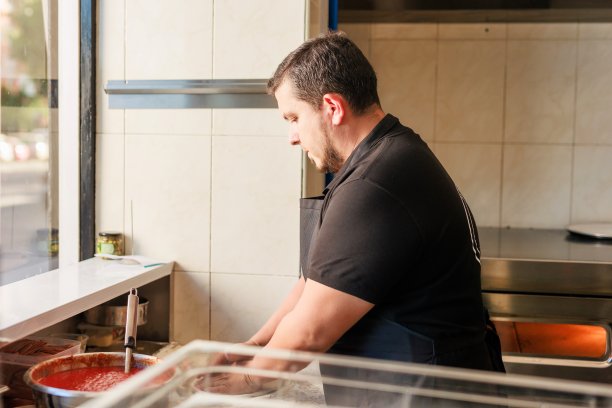 拉丁披萨店厨师穿着专业制服烹制披萨。意大利料理企业家图片下载