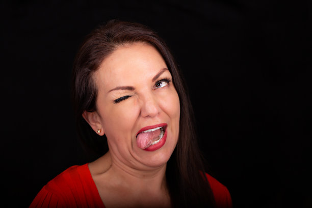 一个40多岁的快乐有趣的女人在工作室里做鬼脸的大头照。图片下载