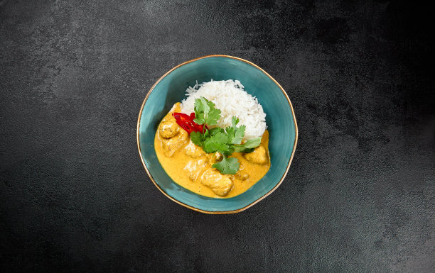 传统的印度食物。咖喱鸡配米饭，陶瓷碗，黑色混凝土背景。亚洲咖喱配鸡肉和印度香米，放在深色石桌上。热菜——辣咖喱。图片下载