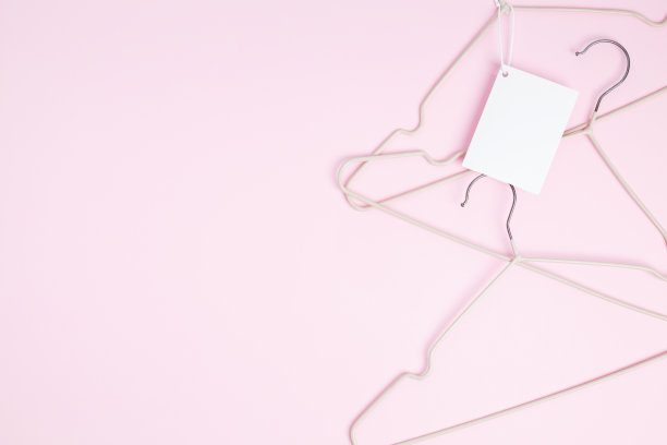创意平铺衣架与白纸标签粉红色的背景。服装吊牌、标签空白模型模板。销售折扣店促销购物概念。前视图。本空间图片下载