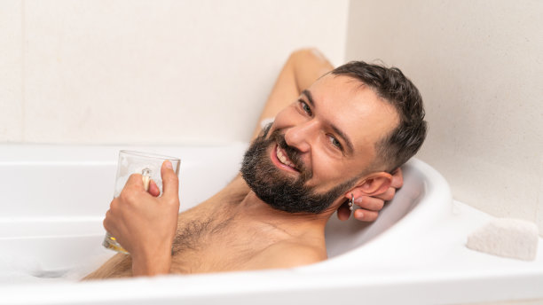 快乐的大胡子男人带着啤酒在洗澡图片下载