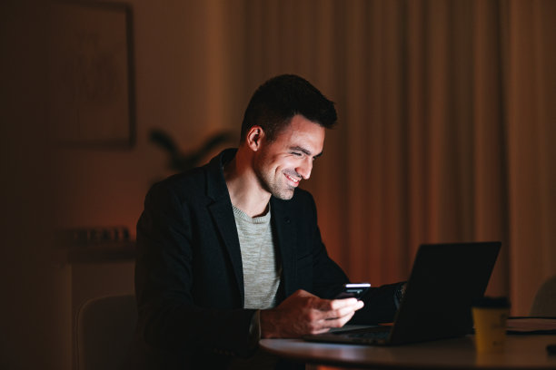 微笑的商人晚上在家里用手机图片下载