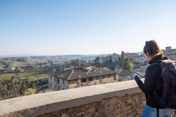 在意大利托斯卡纳的一个村庄里，一名妇女正在使用她的手机图片下载