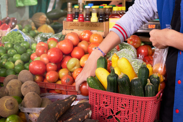 一个不认识的男人在商场的水果摊用塑料袋包装蔬菜图片下载
