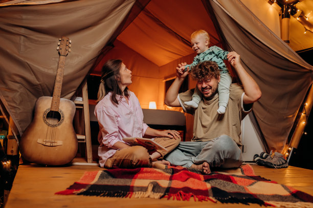 快乐的家庭和可爱的宝宝一起玩耍，在夏天的晚上一起露营。户外休闲休闲的豪华露营帐篷。生活方式的概念图片下载