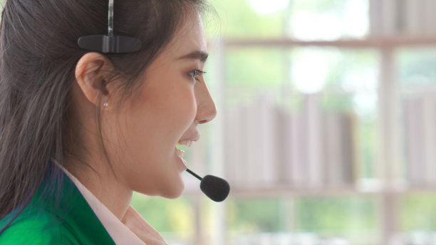 女商人戴着耳机在办公室积极工作。呼叫中心、电话营销、客服为客户提供电话视频会议服务。图片下载