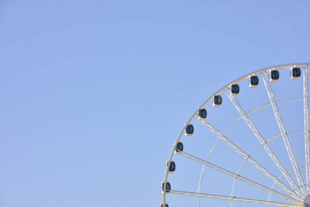 巨大的摩天轮映衬着柔和的蓝天图片下载