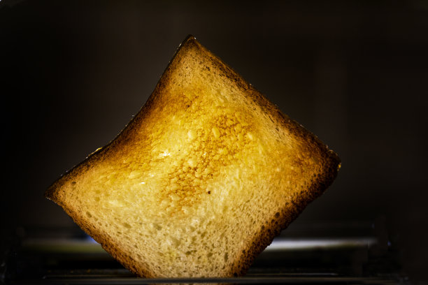 黑色背景的烤面包机里热的烤白面包片。水平图片下载