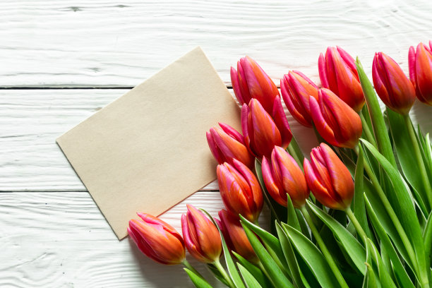 一束郁金香和一张在木质背景上写文字的纸。图片下载