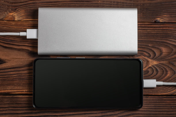木制背景的白色充电宝和智能手机。图片下载