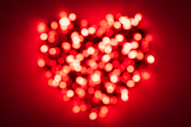 严重模糊的红光从花环形成一个心形的红色背景与晕晕效果图片下载