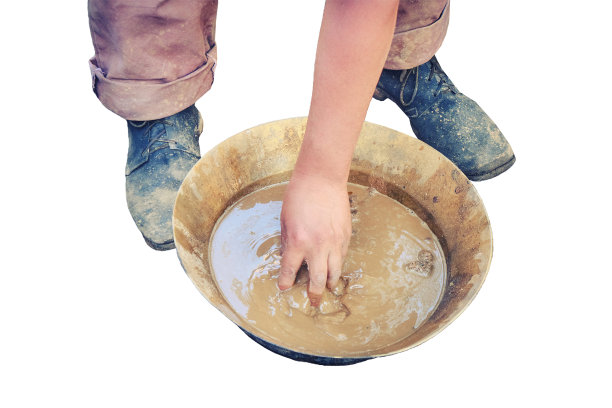 一名男子在白色背景的铜盘里洗金沙。美国拓荒者在克朗代克岛用托盘洗金图片下载