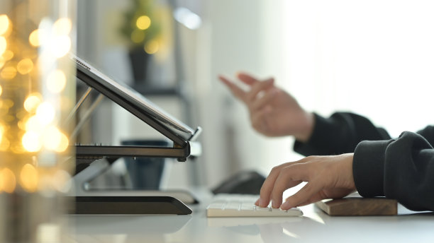 年轻女子自由职业者在无线键盘上打字和在办公桌上使用笔记本电脑的剪裁镜头。图片下载