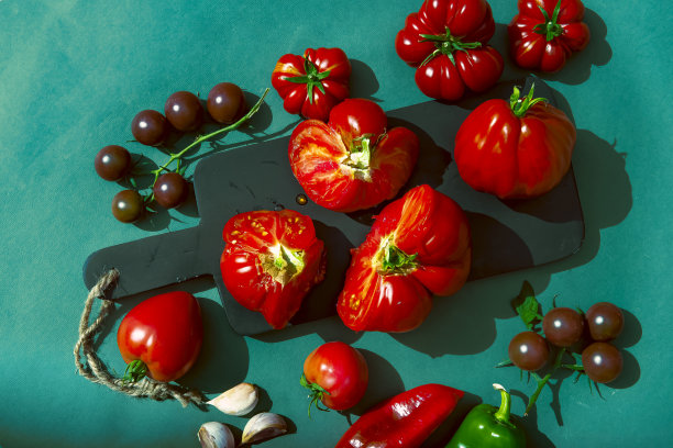 一张明亮的图片，上面有蔬菜，西红柿和彩色背景。多汁的番茄果肉吸引注意力，增强欲望。这是广告中的一个好主意。横幅。农场的蔬菜。这个概念图片下载