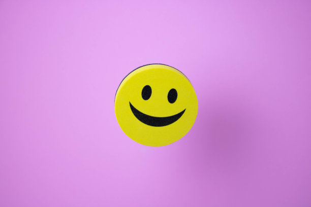 一个黄色的笑脸和它在粉红色背景上的影子。图片下载