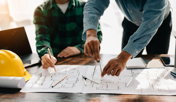 在现代城市的建筑工地上，工程师团队开会一起工作，戴着工人头盔和安全帽。亚洲行业专业团队图片下载