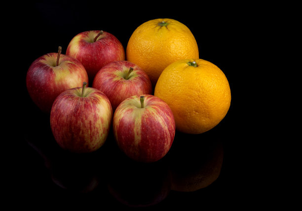 橙色和苹果水果在反光的黑色表面图片下载