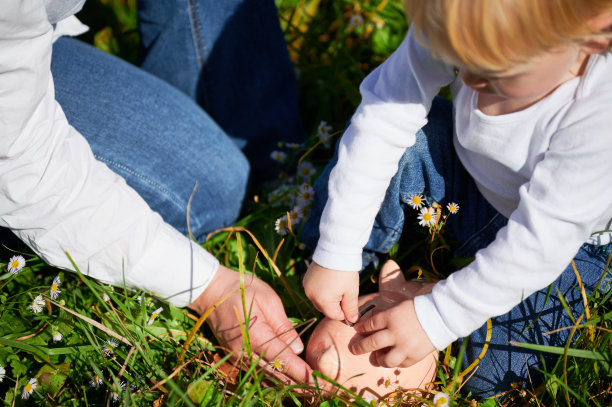 儿子和年轻的妈妈一起存钱，把钱放进储蓄罐。图片下载