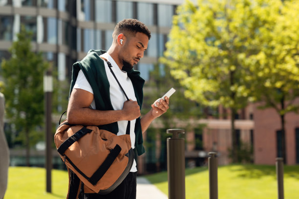 好看的非裔美国人时髦的家伙在手机上在线消息，在城市地区散步，在户外休息图片下载