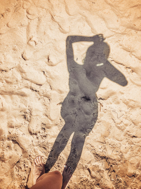 女孩的影子落在沙滩上图片下载