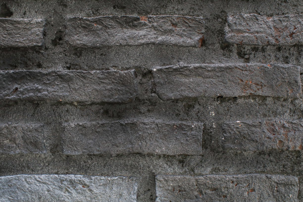 靠近旧的灰色砖墙背景。枯燥乏味的纹理。黑色的壁纸。黑暗的表面。抽象建筑壁纸图片下载