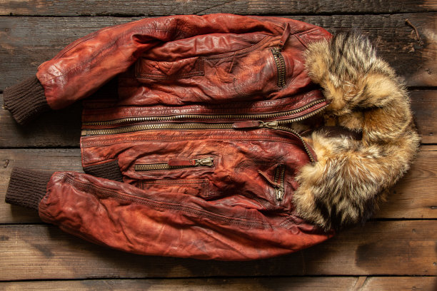 女子的红色冬季皮袄躺在一张旧木桌上，冬季皮袄图片下载