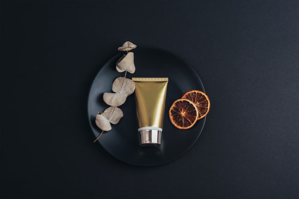 金黄色奶油管和干橙片，尤加利叶放在黑色盘子上。俯视图，平面布局，模型图片下载