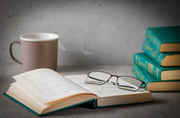 隐私的氛围。桌子上有一堆书、玻璃杯和一本打开的书。背景是一杯茶图片下载
