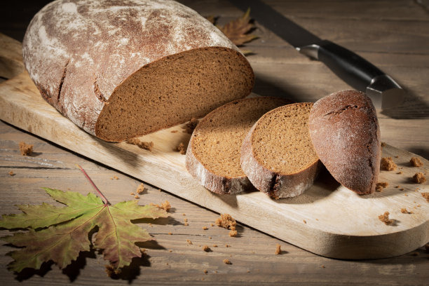 切好的农民黑麦面包放在木桌上。Vignetted照片图片下载
