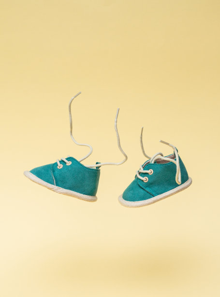 一双飞行的婴儿鞋鞋带在黄色的背景。带有悬浮效果和复制空间的童年概念图片下载