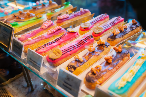 在商店的橱窗和货架上有很多色彩丰富的泡芙。不同种类的法式甜点图片下载