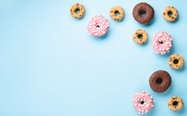 巧克力甜甜圈，粉色棉花糖和糖洒在蓝色的背景图片下载