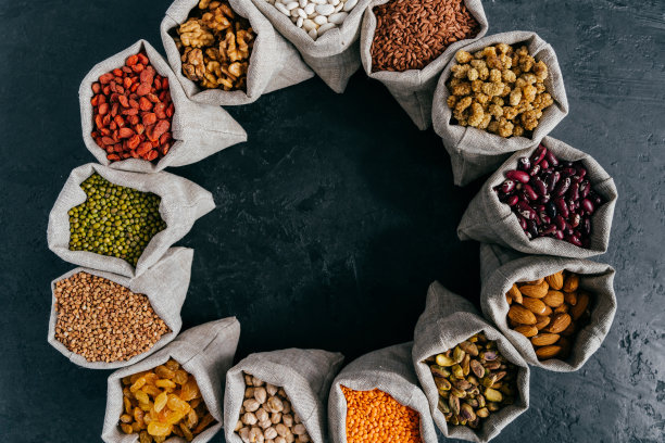 食物和营养概念。横放的装满蛋白质丰富的干果和豆类的袋子。杏仁，核桃，葡萄干，粉色的种子。图片下载
