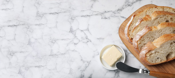 新鲜出炉的面包和黄油放在白色大理石桌子上，平整的桌子上留有文字空间。旗帜设计图片下载