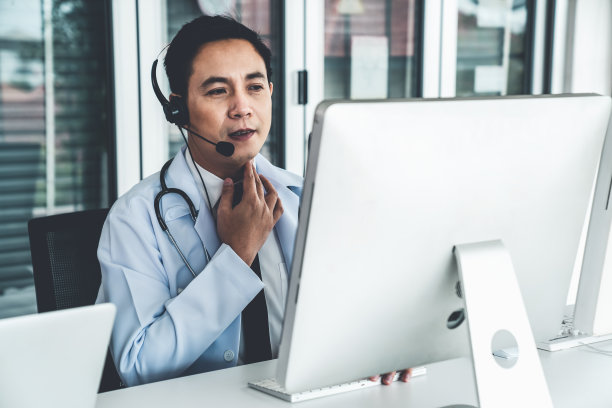 医生戴着耳机在诊所或医院积极视频通话。远程保健和远程医疗服务的概念。图片下载