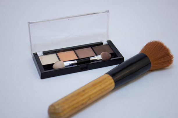 白色背景上放着眼影盘和蓬松的化妆刷。为女性美丽的事物创造独特的妆容。眼影和刷子的概念。图片下载