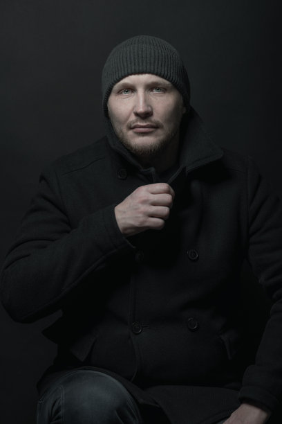 严肃的男子与黑色冬季大衣和冬季帽子的工作室肖像图片下载