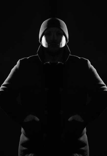 穿着外套和帽子的男人隐藏在阴影和剪影中，被光照亮图片下载