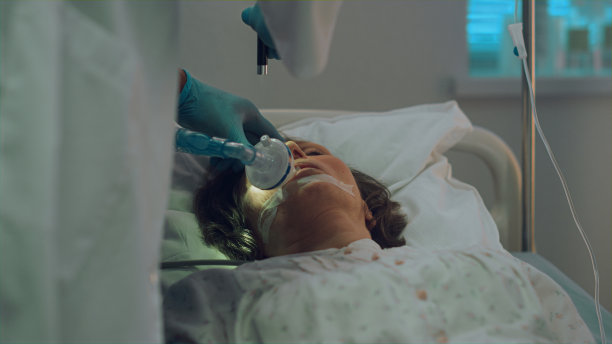 病人在病床上呼吸氧气面罩。医生测试光反射特写图片下载