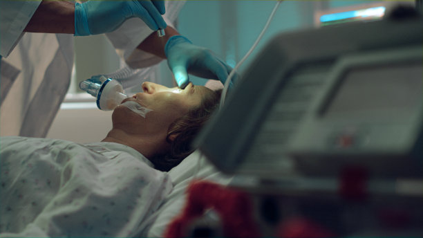 医生在重症监护室用手电筒测试病人氧气面罩。图片下载