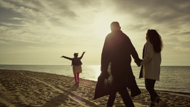 一家人在可爱的自然散步上看日落海滩。人们成群结队地享受海洋海岸。图片下载