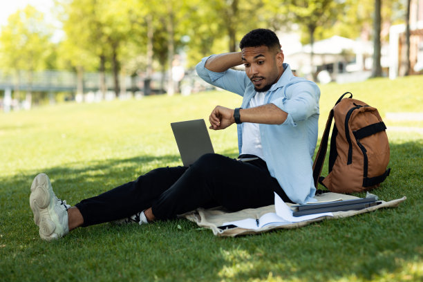 年轻的男性自由程序员，坐在公园里用笔记本电脑工作，加班后感到震惊图片下载