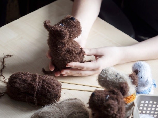 一个年轻女子手里的针织玩具。针织理念，手工制作，心灵健康的活动。图片下载